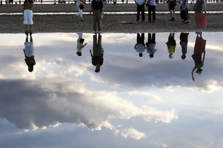 Silhouette of many people on a sea beach. Reflection on a beach.
