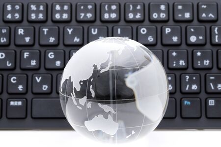 Glass globe ball with keyboard on white backgroundの写真素材