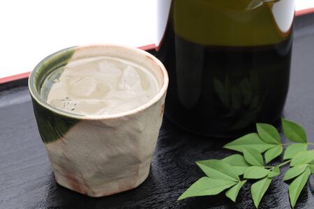 Bottle of Japanese shochu and ceramic bowl on wooden trayの写真素材