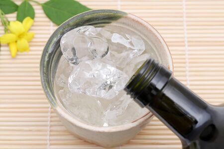 Bottle of Japanese shochu and ceramic bowl on bamboo tableの写真素材
