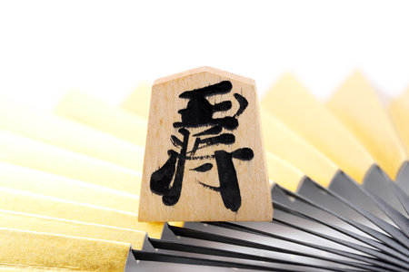 Japanese Shogi pieces and Sensu on a white background, Shogi is Japanese chess. Word that is written...