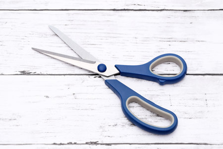 blue handled scissors on a white wooden tableの写真素材