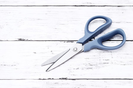 blue handled scissors on a white wooden table
