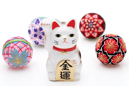Japanese lucky cat with Temari ball on white background, Japanese word of this photography means "economic fortune"の写真素材
