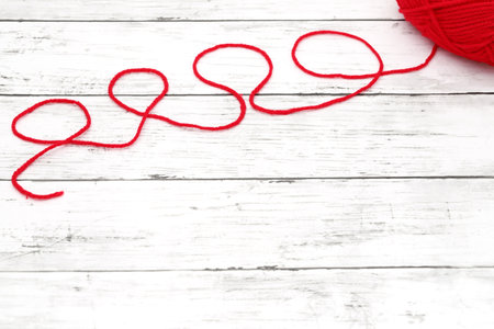 Red ball of wool yarn on a white wooden tableの写真素材