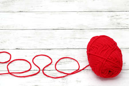 Red ball of wool yarn on a white wooden tableの写真素材