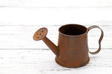 rusted old miniature watering can on wooden white tableの写真素材