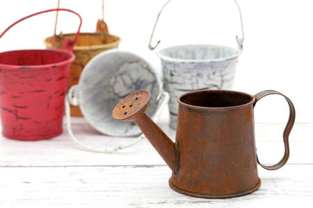 rusted old miniature watering can wiht bucket on wooden white tableの写真素材