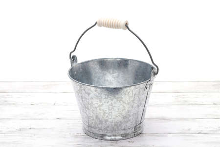 Empty metal bucket on white grunge wooden tableの写真素材