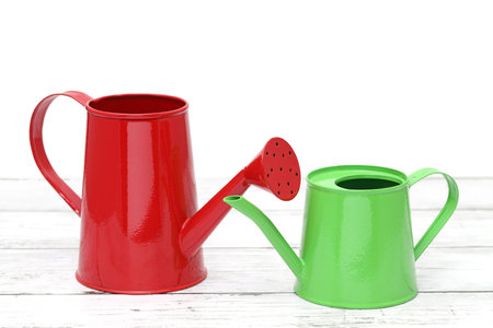 green and red watering can on white wooden tableの写真素材