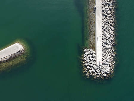 Aerial view of jetty with concrete blocks, white jetty against blue waterãの写真素材