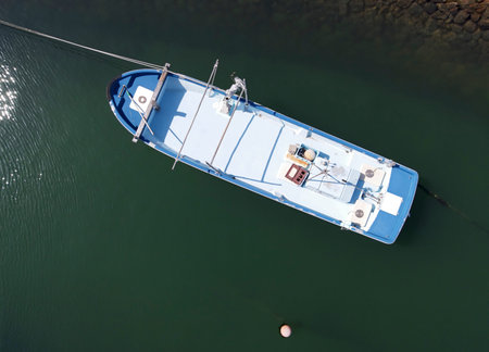 Aerial view of fishing boat moored against a background of deep green sea water