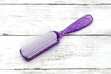 Fashionable female comb for hair care on a white wooden tableの写真素材