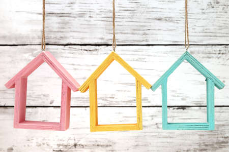 Wooden miniature houses hanging by strings on white grunge wallの写真素材