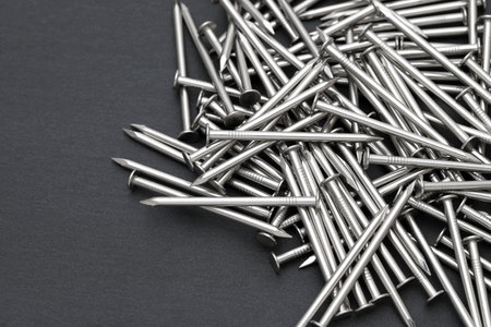 Pile of silver metallic nails on black background
