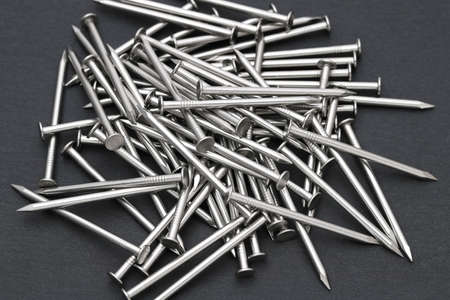 Pile of silver metallic nails on black backgroundの写真素材