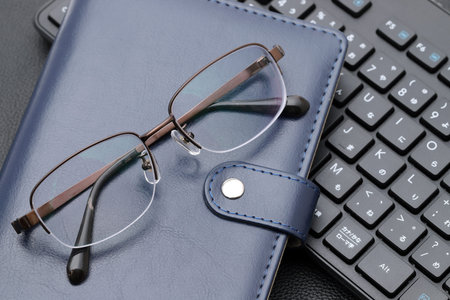 Eyesight glasses with note book, computer keyboard. Alphabetics and Japanese hiragana typing...