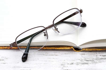 Stylish eyesight glasses and opened notebook on white wooden tableの写真素材