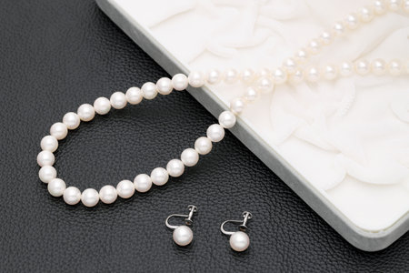 Elegant white pearl necklace and earrings on black backgroundの写真素材
