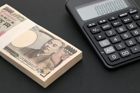 Japanese salary envelope and calculator, The banknotes are written as "10,000 yen" in Japanese.の写真素材