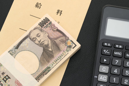 Japanese salary envelope and calculator, Translation: Salary, The banknotes are written as "10,000 yen" in Japanese.の写真素材