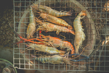 Grilled river prawns with butter and herb on flaming grill (vintage color)の写真素材