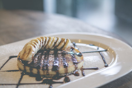 Retro effect faded image of pancakes With Chocolate Syrup and banana sliced  soft focusの写真素材