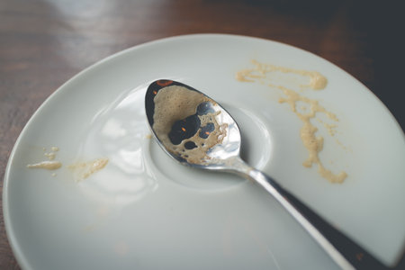 Coffee stain on metal spoon and white ceramic dish.Filtered image processed vintage effect.の写真素材