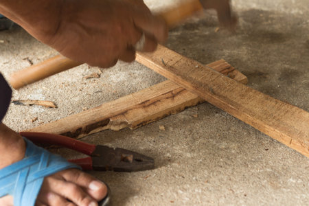 The carpenter is hitting a nail to the wood planksoft focusの写真素材
