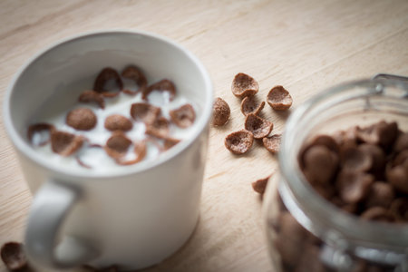 milk and chocolate cereal cornflakes in white cup that ready for serving in breakfast time