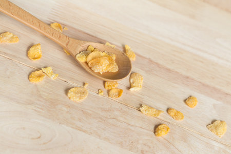 cereal cornflakes spilling out from the wood spoon to wood floorの写真素材