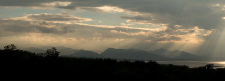 Sun rays during sunrise over the moutain and lake, Thailand