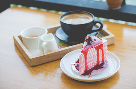 strawberry crape cake and hot coffee. strawberry crape cake with strawberry sauce. strawberry crape cake in cozy outdoor cafe.(selective focus)の写真素材