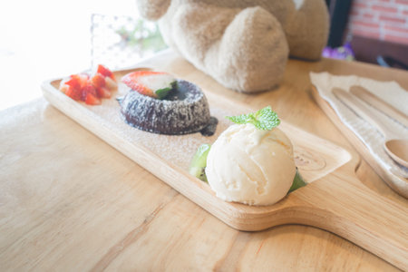 chocolate lava cake with vanilla ice cream and strawberry. chocolate lava on wood plate. Hot chocolate pudding with fondant centre.(selective focus)の写真素材