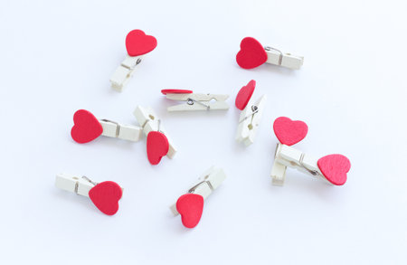 wooden clothes pin or cloth pegs with heart shape design on a white backgroundの写真素材