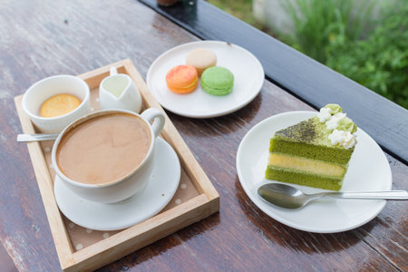 hot coffee breakfast set with green tea cake and fresh macaroon in cozy outdoor cafeの写真素材