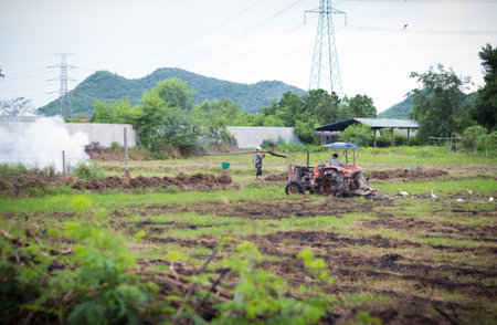 Farmer in tractor preparing land with seedbed cultivatorの写真素材