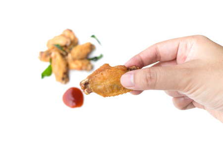 hand holding fried chicken wings and ketchup isolated on white backgroundの写真素材