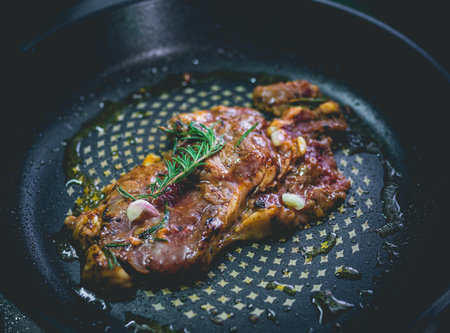 Beef steak with rosemary, garlic, salt and pepper inside iron skilletの写真素材