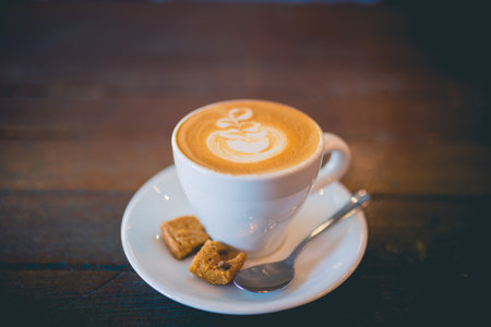 Picture of latte hot coffee with foam milk art on a wooden tableの写真素材
