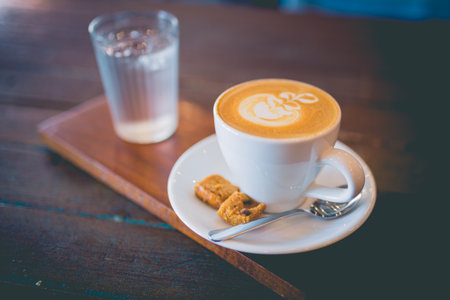 Picture of latte hot coffee with foam milk art on a wooden tableの写真素材