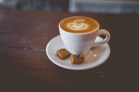 Picture of latte hot coffee with foam milk art on a wooden tableの写真素材