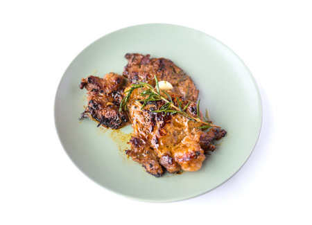 Round plate with grilled beef steak and rosemary isolated on white backgroundの写真素材