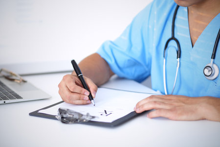 Portrait of unknown male surgeon doctor holding his stethoscope and filling up medical prescriptionの写真素材