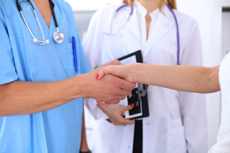 Male doctor and female patient shaking hands. Partnership, trust and medical ethics conceptの写真素材