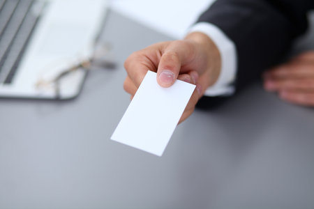 Close-up of  businessman giving a business card, sitting at the tableの写真素材