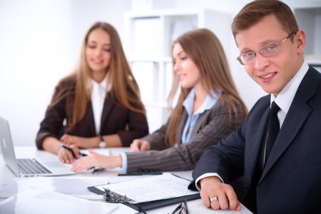 A group of business people at a meeting on the background of office. Focus on a businessmanの写真素材