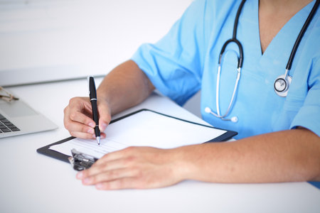 Portrait of unknown male surgeon doctor holding his stethoscope and filling up medical prescriptionの写真素材