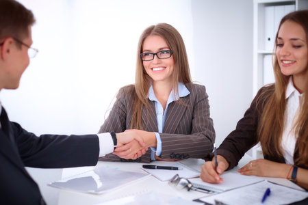 Business handshak  sitting at the desk on office background, copy space area at the left upper cornerの写真素材