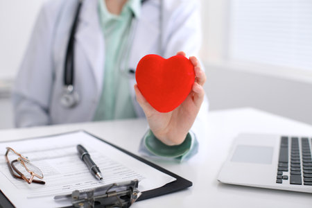 Female doctor with stethoscope holding heart.   Cardio therapeutist, physician make cardiac physical, heart rate measure, arrhythmia, old age life conceptの写真素材
